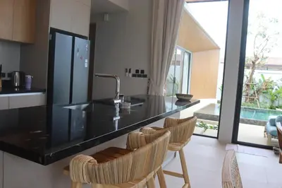 a kitchen with a black counter and some chairs at Botanica Four Season Luxury Pool Villa in Phuket