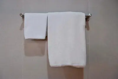three white towels hanging on a towel rack in a bathroom at Tree House in Ban Rangeng