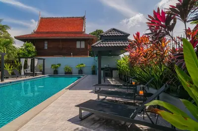 a swimming pool with benches next to a villa at Greenleaf Estate - 3bedroom Villa with large shared pool, Nai harn beach in Rawai Beach