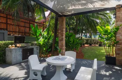 a patio with a table and chairs and a fireplace at Greenleaf Estate - 3bedroom Villa with large shared pool, Nai harn beach in Rawai Beach