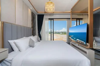 a bedroom with a large white bed and a flat screen tv at Apartment in Laguna perfect location in Laguna Phuket
