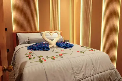 two white swans sitting on a bed with flowers at Bauman Residence in Patong Beach
