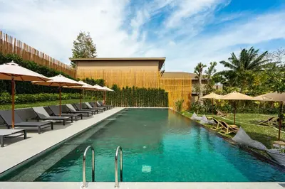 a swimming pool with chairs and umbrellas next to a building at Chaykha Retreat