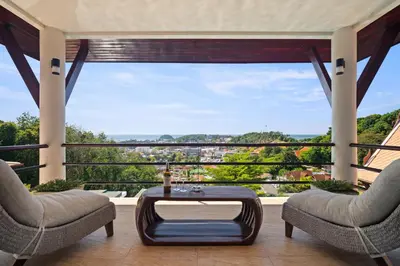 a living room with a table and chairs and a large window at Kata Seaview Villa in Ban Karon