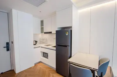 a kitchen with a refrigerator and a table and chairs at KORA 243 One-Bedroom Residence in Phuket Town