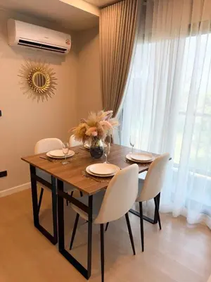 a dining room table with chairs and a vase of flowers on it at Stylish 2BR condo in the heart of Bang Tao in Ban Thalat Choeng Thale