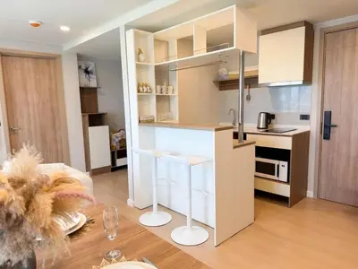 a kitchen with white cabinets and stools in a room at Stylish 2BR condo in the heart of Bang Tao in Ban Thalat Choeng Thale