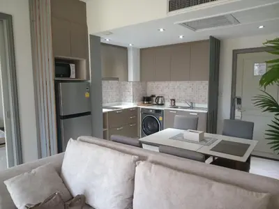 a living room with a couch and a kitchen at Allamanda Laguna Phuket Apartment in Bang Tao Beach