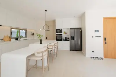 a kitchen with white floors and a counter with stools at Pool Villa Rawai, Phuket Lay Pearl in Ban Saiyuan (1)