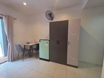 a room with a refrigerator and a table with a clock on the wall at Chokdee rooms kata in Kata Beach