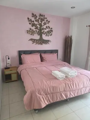 a bedroom with a pink bed with two towels on it at Chokdee rooms kata in Kata Beach
