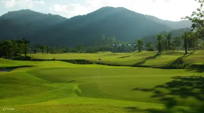 a green golf course with mountains in the background at Phuket sun n soul House in Ban Tha Rua