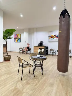 a room with tables and chairs and a woman sitting in a room at Top Hotel Patong in Patong Beach
