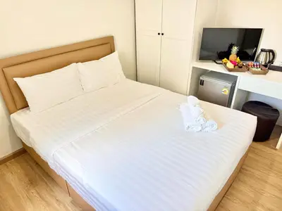 a bedroom with a bed with white sheets and a desk at Top Hotel Patong in Patong Beach