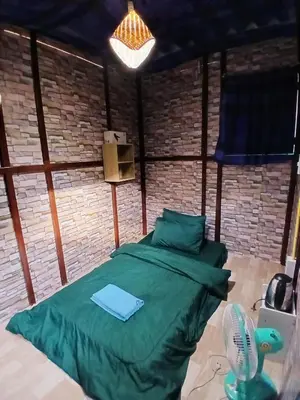 a bedroom with a green bed and a fan at Kalaland in Patong Beach
