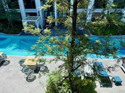 a tree with chairs and a table next to a pool at Stylish Apartments in a New Boutique Complex in the Laguna in Laguna Phuket