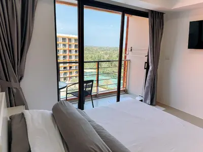 a bedroom with a bed and a view of a balcony at FAMILY HOMES Panoramic Pool View Studio in Mai Khao CB-706 in Ban Mai Salae