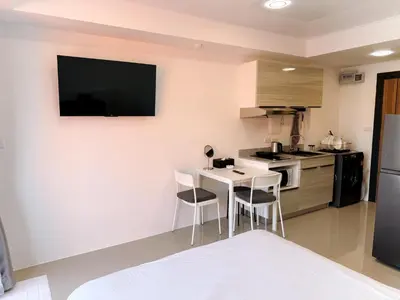 a kitchen with a table and chairs and a television on the wall at FAMILY HOMES Panoramic Pool View Studio in Mai Khao CB-706 in Ban Mai Salae