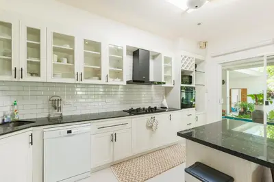 a kitchen with white cabinets and a black counter top at Peaceful Villa 12 mins to Bangtao & Layan Beach in Ban Pak Lak