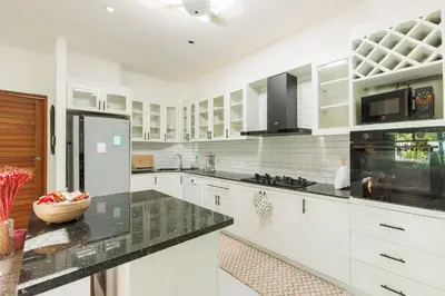 a kitchen with white cabinets and black counter tops at Peaceful Villa 12 mins to Bangtao & Layan Beach in Ban Pak Lak