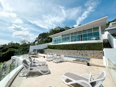a patio with lounge chairs and a building at Villa Neptune Phuket - Luxury 6BR with Private Pool, Chalong in Ban Klang