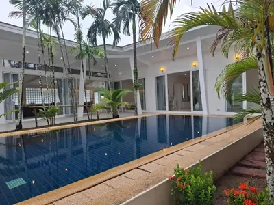 a swimming pool in a villa with palm trees at Mango Villa in Ban Pa Khlok