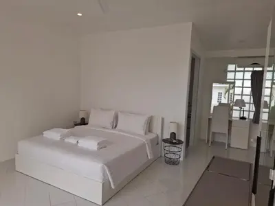 a white bedroom with a white bed and a table at Mango Villa in Ban Pa Khlok