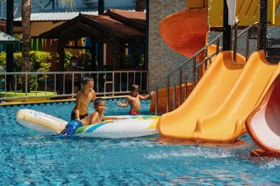 a group of young boys playing on a water slide in a pool at Love Rawai Hotel in Rawai Beach