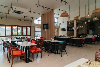 a restaurant with tables and chairs and a tv at Love Rawai Hotel in Rawai Beach