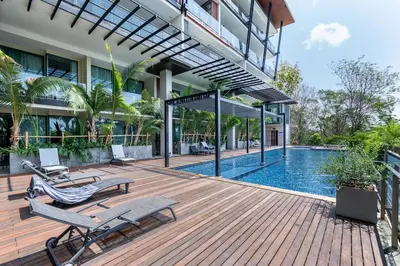 a wooden deck with chairs and a swimming pool at Spacious studio with big patio ! in Rawai Beach