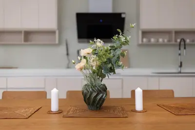 a vase of flowers on a table with two candles at Taimana Luxury 3BR Private Pool Villa at LuxPride in Ban Phak Chit