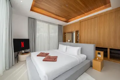 a bedroom with a large white bed and a television at Taimana Luxury 3BR Private Pool Villa at LuxPride in Ban Phak Chit