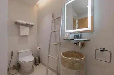 a bathroom with a toilet and a mirror and a sink at Taimana Luxury 3BR Private Pool Villa at LuxPride in Ban Phak Chit