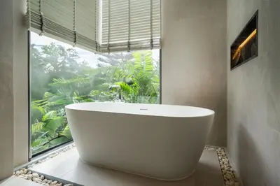 a bathroom with a white tub in front of a window at Menara Luxury 4 Bedroom Private Pool Villa BangTao in Ban Phak Chit