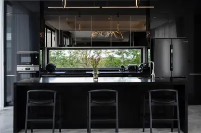 a kitchen with a black island with two bar stools at Menara Luxury 4 Bedroom Private Pool Villa BangTao in Ban Phak Chit