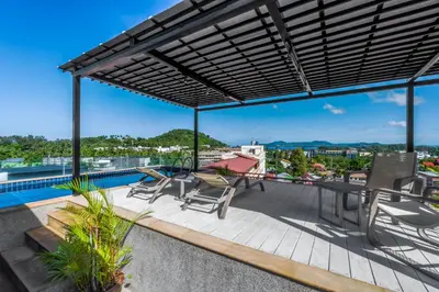 a patio with a table and chairs on a roof at Surin Sabai in Surin Beach