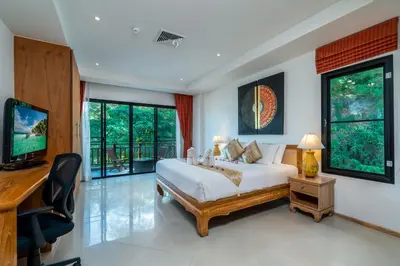 a bedroom with a bed and a desk and a television at Surin Sabai in Surin Beach