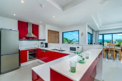 a kitchen with red cabinets and a white counter top at Surin Sabai in Surin Beach