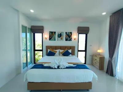 a bedroom with a large bed with blue and white sheets at Jitvirat Pool Villa in Ban Nong Chaeng