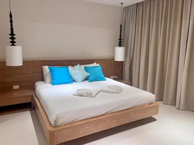 a bedroom with a large bed with blue pillows at Top Pick Brand New Modern Resort Pool Villa in Laguna Phuket