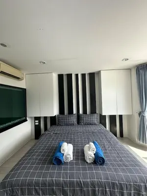 a bedroom with a bed with two pillows and a tv at Grand Patong Apartment 6FL in Patong Beach
