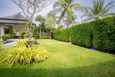 a garden with a hedge and a bench in a yard at Beautiful Pool Villa in Pavilion and Tropical Oasis in Ban Pak Lak