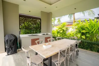a wooden table and chairs in a room with a kitchen at Beautiful Pool Villa in Pavilion and Tropical Oasis in Ban Pak Lak