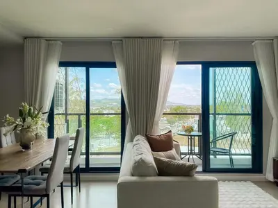 a living room with a couch and a table with chairs at Comfortable 2Bdr Bangtao Space Condo in Ban Thalat Choeng Thale
