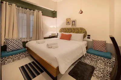 a bedroom with a large bed and two chairs at Chinoir Boutique Phuket Town in Phuket