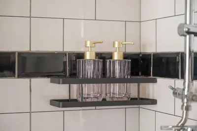 a shelf with two glasses and two faucets in a bathroom at Chinoir Boutique Phuket Town in Phuket