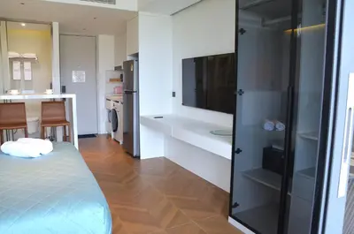 a room with a bed and a tv and a kitchen at The Sunshine Beach studio with a great view in Layan Beach