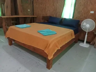 a bedroom with a bed with blue sheets and a fan at Kohyaonoi Lastfisherman in Ko Yao Noi