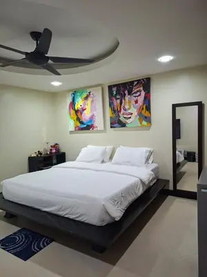 a bedroom with a large bed with paintings on the wall at The Aspasia Kata Beach in Kata Beach