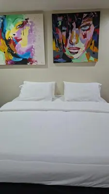 a white bed with two paintings on the wall at The Aspasia Kata Beach in Kata Beach